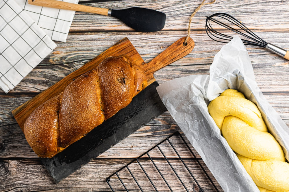 cosonac copt pe un tocator  langa un cozonac necopt in tava