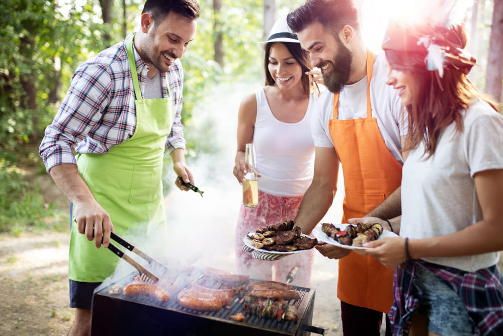 persoane care prepara carne si legume la gratar