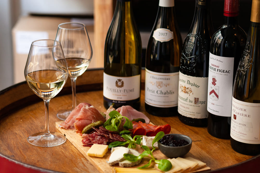 sticle de vin langa un platou cu branza si mezeluri