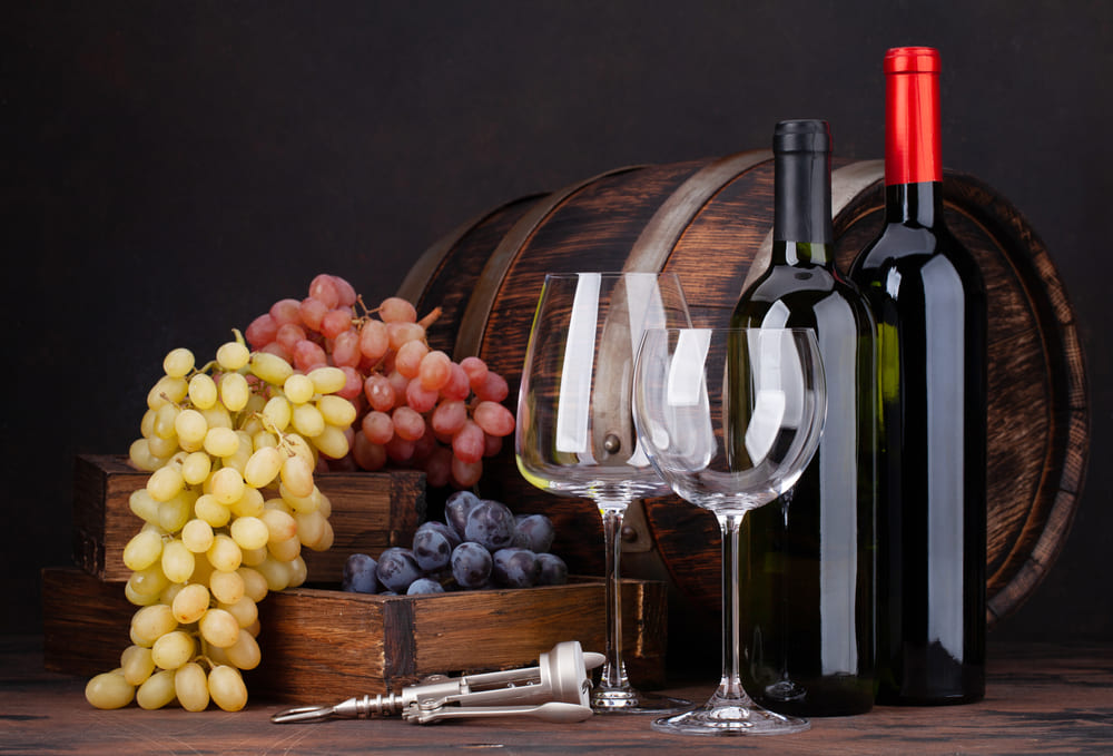 sticle si pahare de vin langa ciorchini de struguri