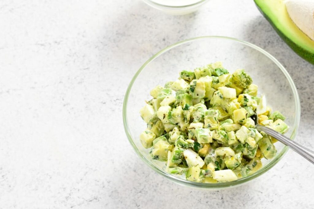 Bol cu salata de oua cu avocado si iaurt pe masa alba