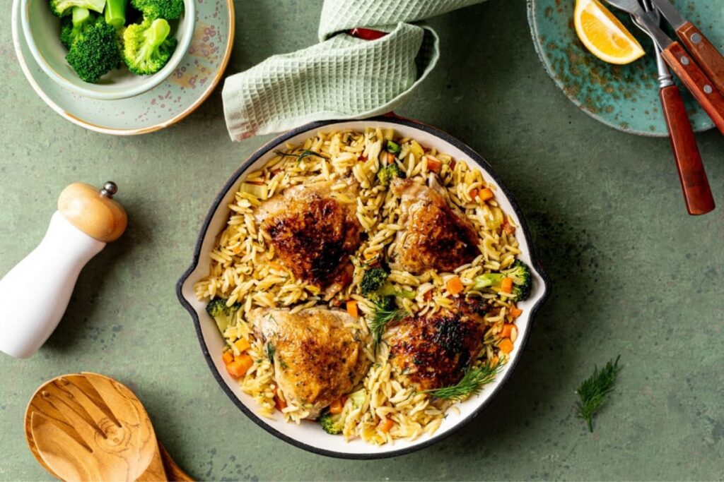 Paste orzo cu pui in cratita din fonta pe masa verde
