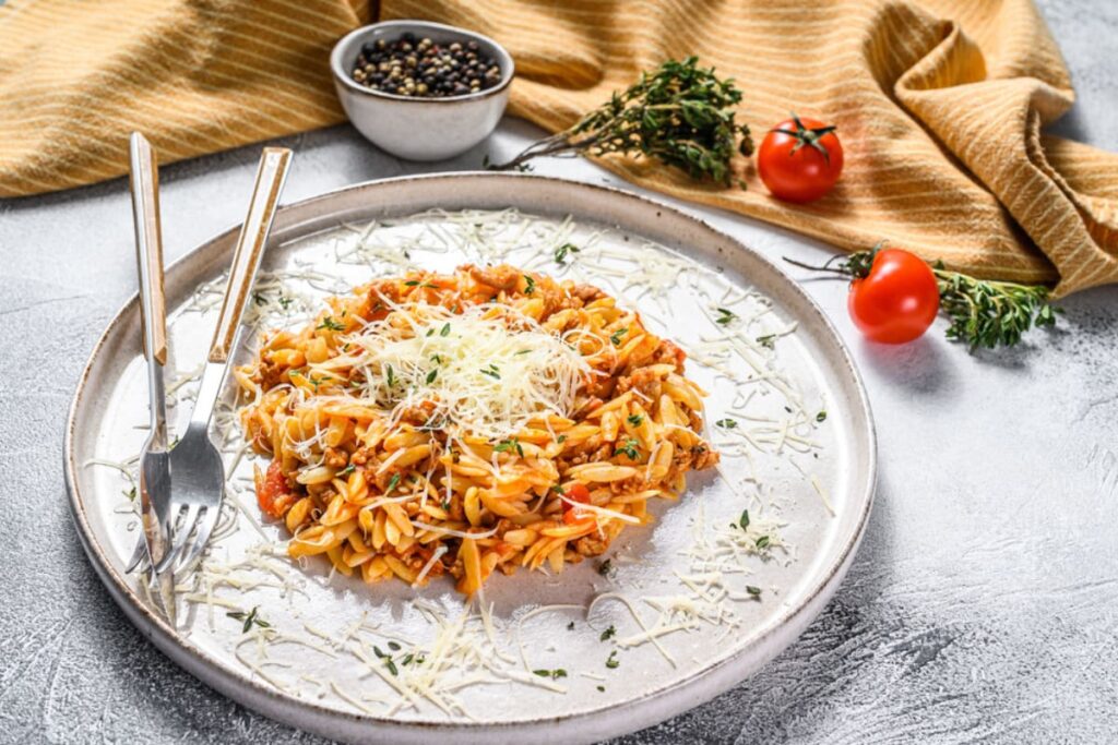 Paste orzo cu sos bolognese si vita in farfurie alba