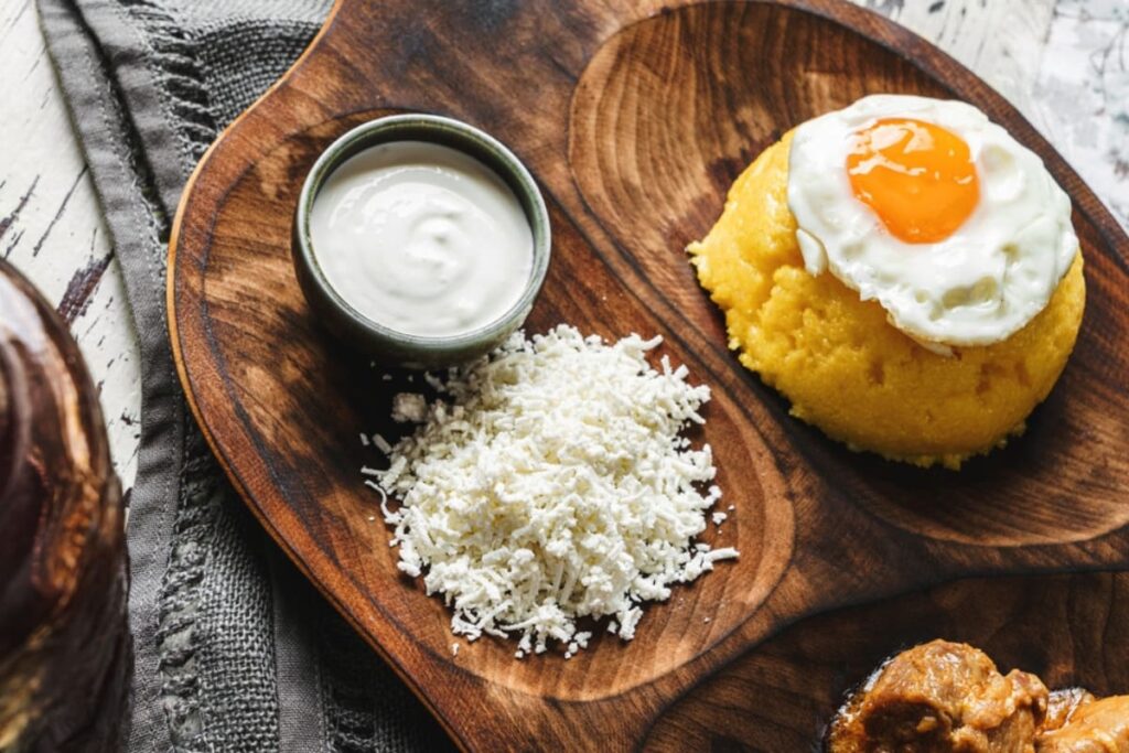 Mamaliga cu ou prajit, branza si smantana pe tava rustica din lemn