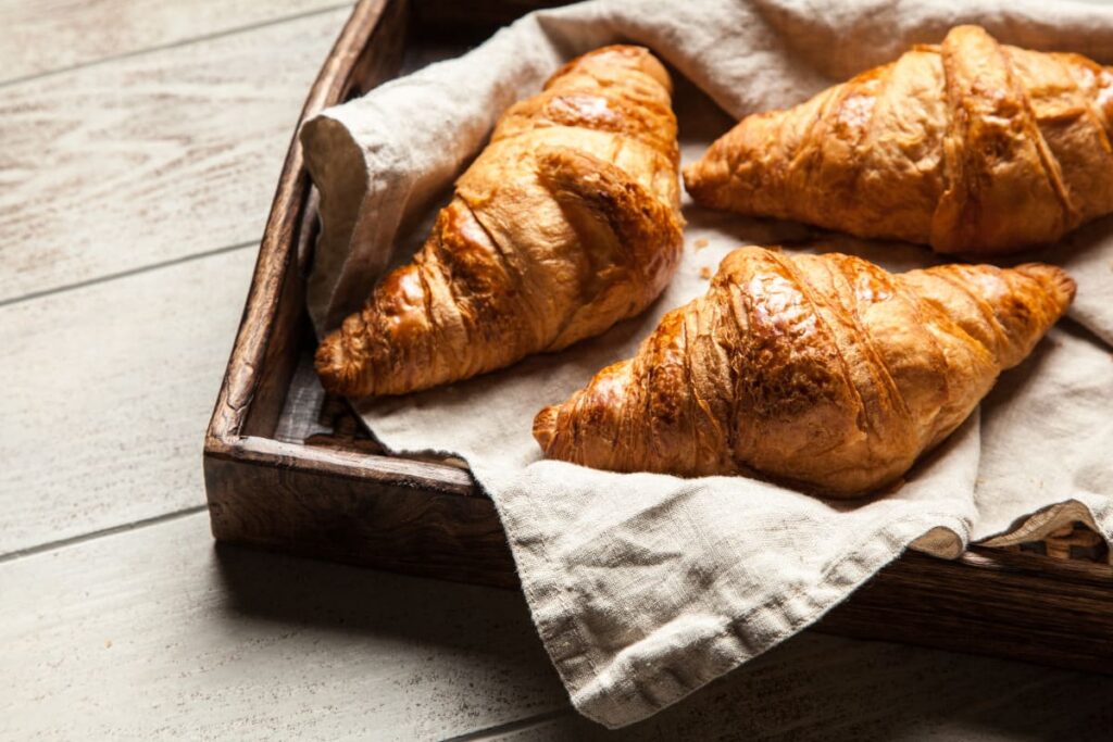Croissante cu unt pe servet in tava din lemn