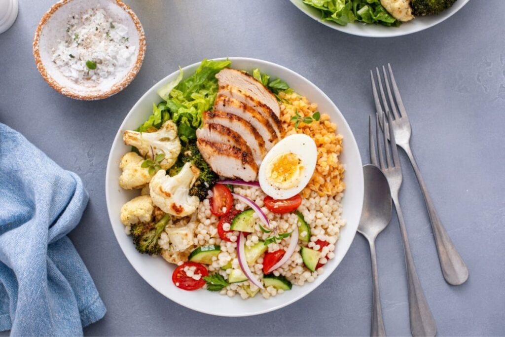 Cuscus cu piept de pui la gratar, ou si legume in farfurie alba