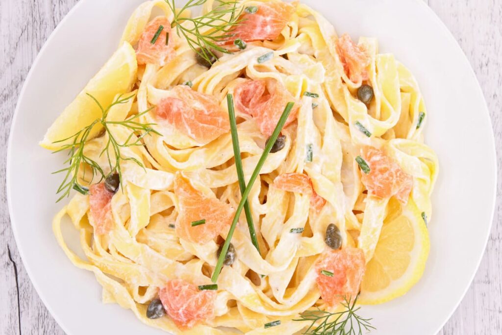 Paste cu somon afumat servite cu lamaie in farfurie alba