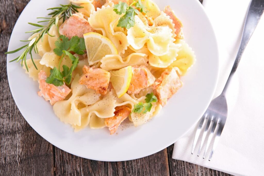 Paste cu somon servite cu patrunjel si lamaie in farfurie alba