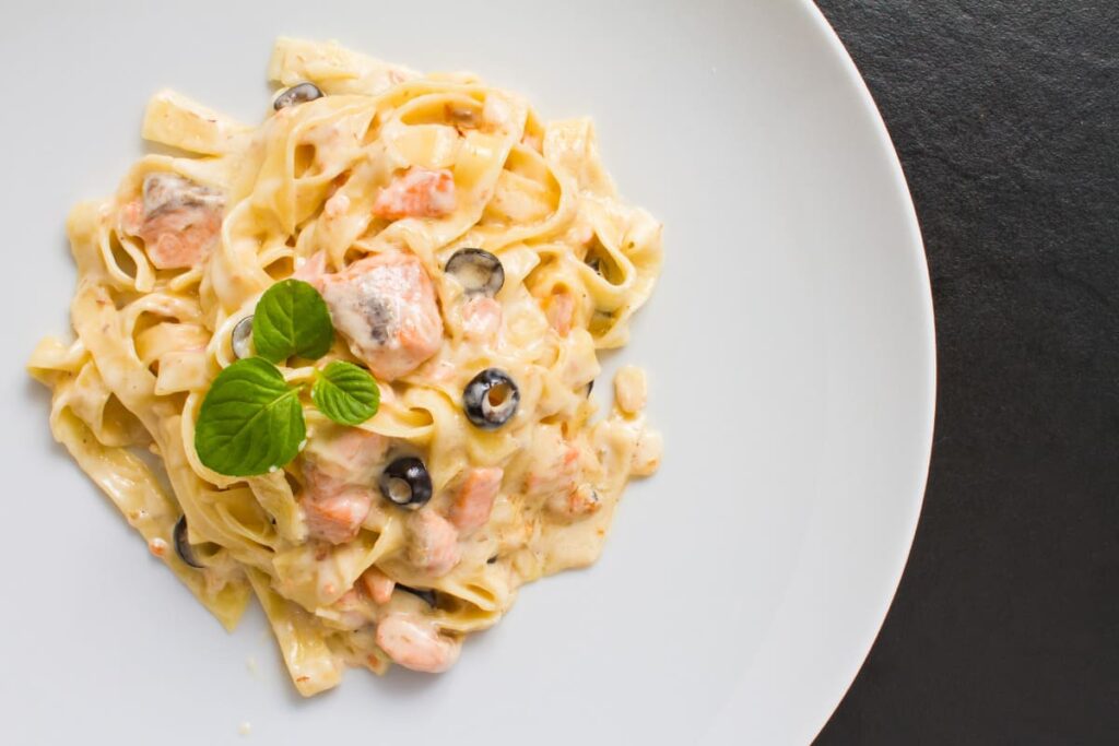 Paste cu somon si smantana servite cu busuioc in farfurie alba