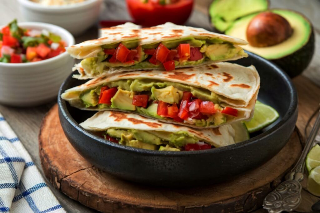 Quesadilla vegana cu avocado si rosii in bol pe tocator rustic