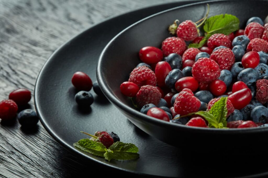 Salata de fructe de padure servita in bol negru cu menta