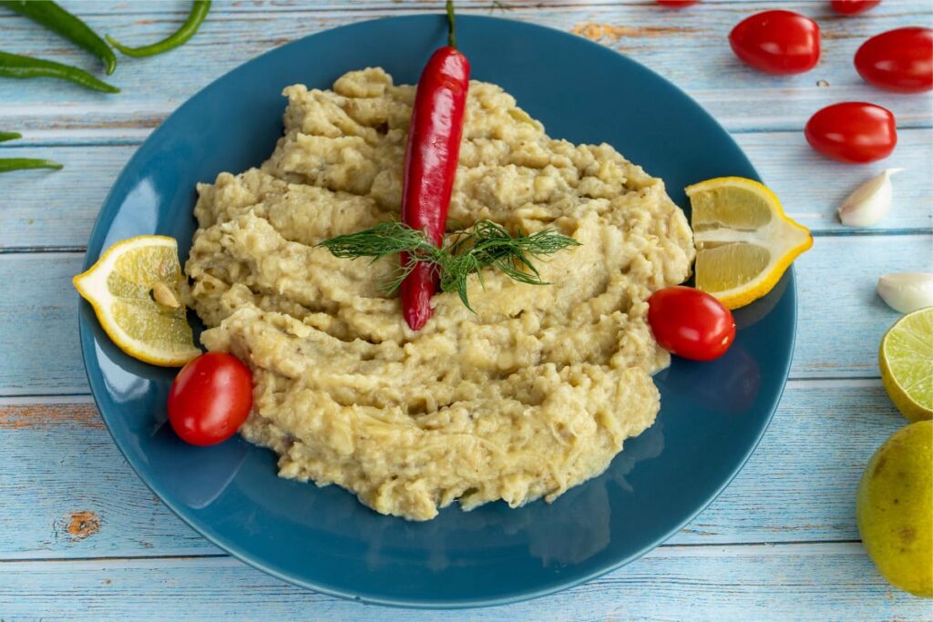 Salata de vinete pe farfurie cu rosii, lamaie si ardei iute
